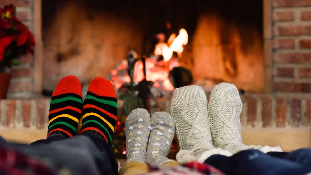 Feet in Christmas socks near fireplace. Family relaxing at home.